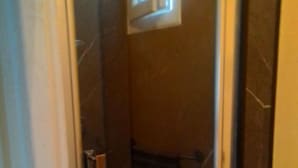 A glass-enclosed shower stall with a small window, a metal towel rack, and a tiled floor. - Franglais flats (Boulogne-sur-Mer)