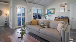 A living room with a sofa, a lamp, a plant, and a view of the outdoors. - Ocean Views & Breezes, Pool, Huge Deck, Serenity (St. Thomas)