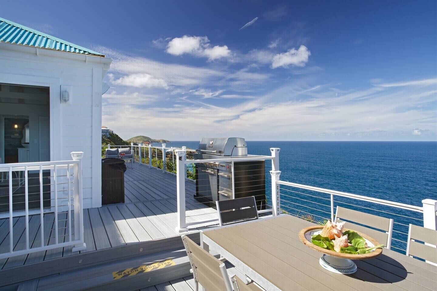 Un terrazzo con barbecue, posti a sedere all'aperto e vista sull'oceano.