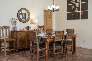 A dining area with a wooden table, chairs, a chandelier, a mirror, and a wall with a floral artwork. - New Listing Private Spa, Pet-Friendly, Pool, Close to Parks, Garage | C419 (Moab)