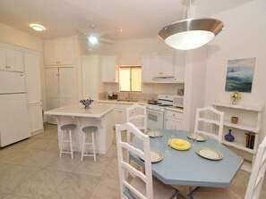 A kitchen with white cabinets, a blue dining table, and a hanging light fixture. - Casa SunnySide Access to Heated Pool. (San Felípe)