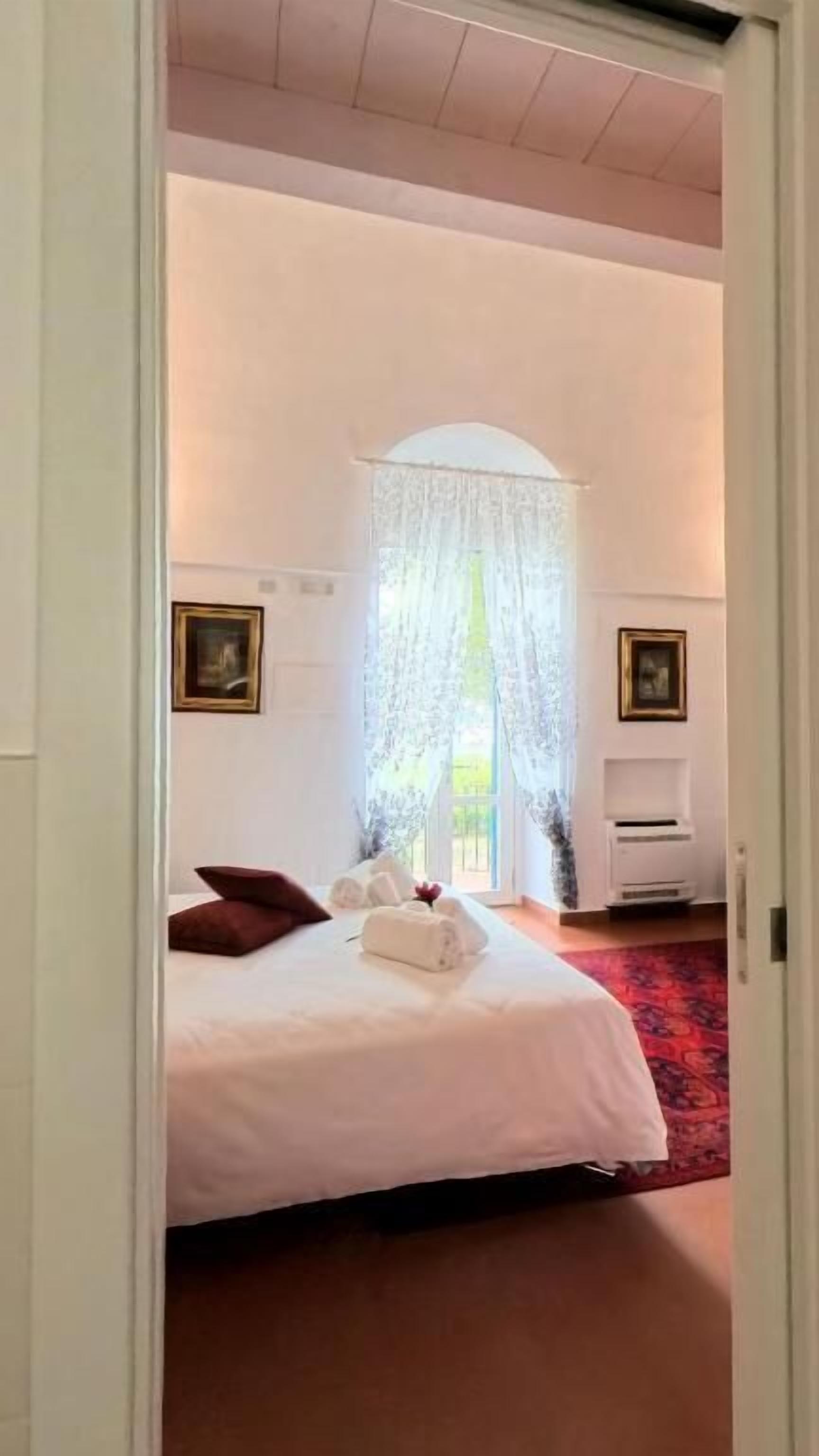 Ein Hotelzimmer mit einem großen Bett, einem roten Teppich und einer weißen Wand mit einem Bilderrahmen.