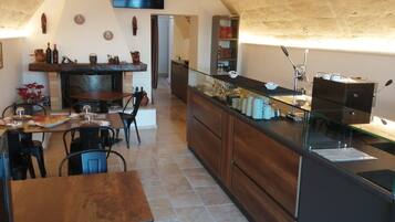A cozy dining area with a fireplace, wooden furniture, and a glass display case with kitchen items.