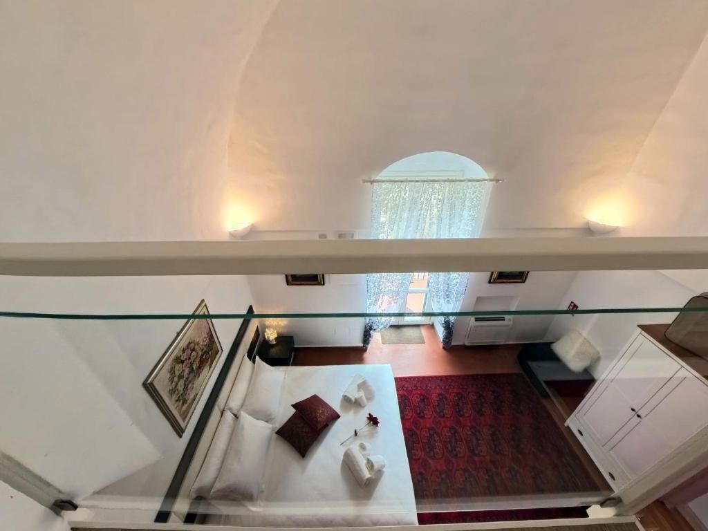A hotel room with a bed, a red carpet, a wardrobe, and a window with curtains.