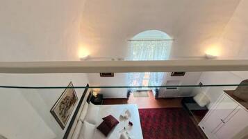 A hotel room with a bed, a red carpet, a wardrobe, and a window with curtains.