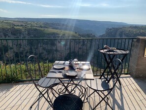 A dining table with chairs on a balcony overlooking a valley. - Villa Sine Tempore Fumarola (Matera)