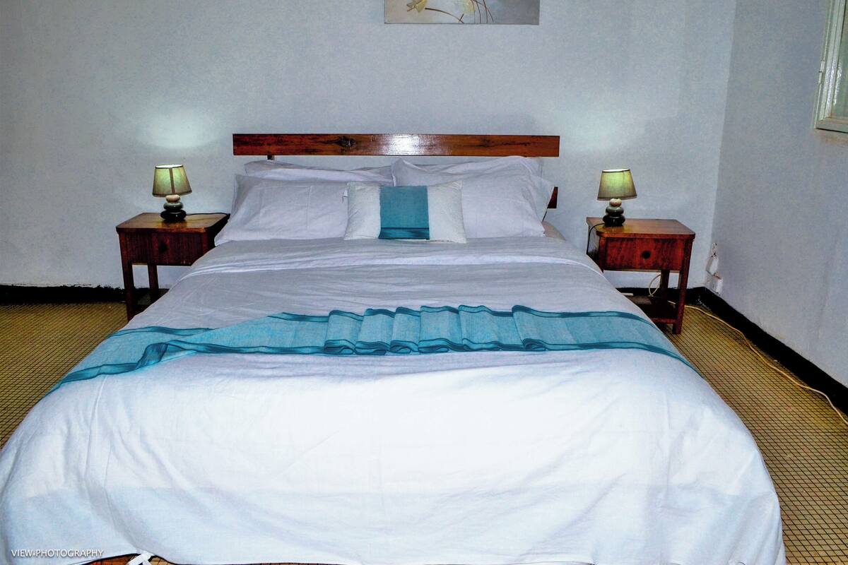 A hotel room with a large bed, two bedside tables, and a wooden headboard.