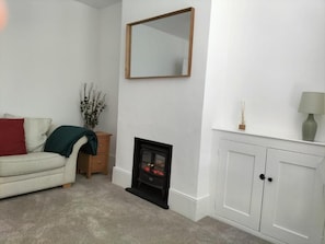 Relax in this stylish living room with a sofa, fireplace, and mirror.