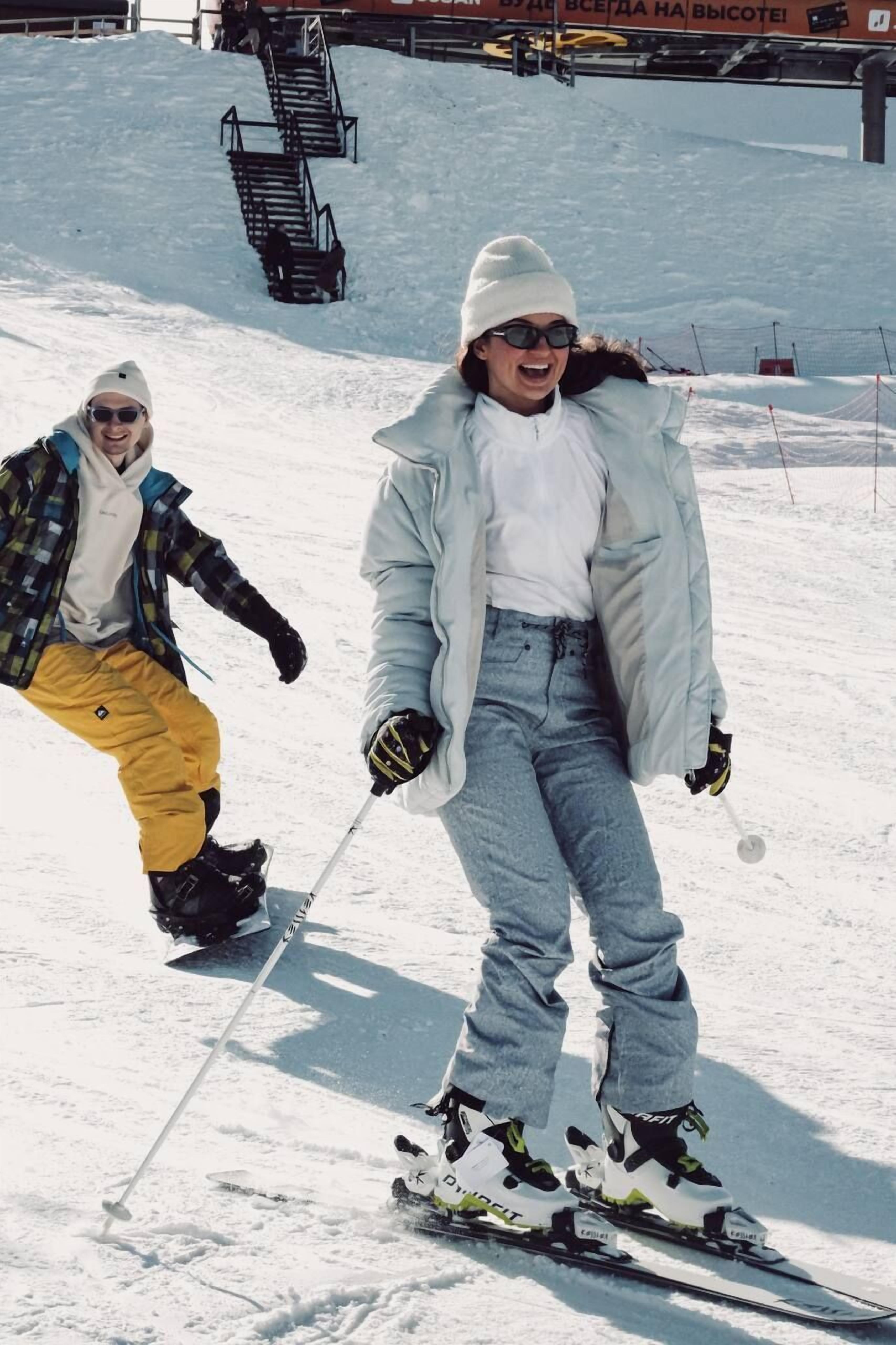 Eine Person fährt auf einem verschneiten Hang Ski, im Hintergrund ist eine Sesselbahn zu sehen.