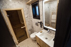 A bathroom with a white tiled floor, a white sink with a soap dish, a mirror, and a toilet.
