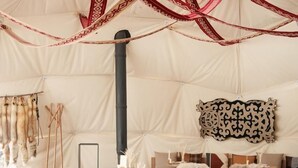 A tented dining area with round tables, fur-covered chairs, and a central black pole. - Tenir Eco Hotel (Almaty)