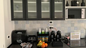 A kitchen with black cabinets, a coffee machine, a bread maker, and various kitchen appliances. - B&B Residence Armonia Sulmona, city center (Sulmona)
