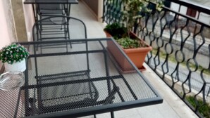 A balcony with a metal table and chairs, potted plants, and a view of the street. - B&B Residence Armonia Sulmona, city center (Sulmona)