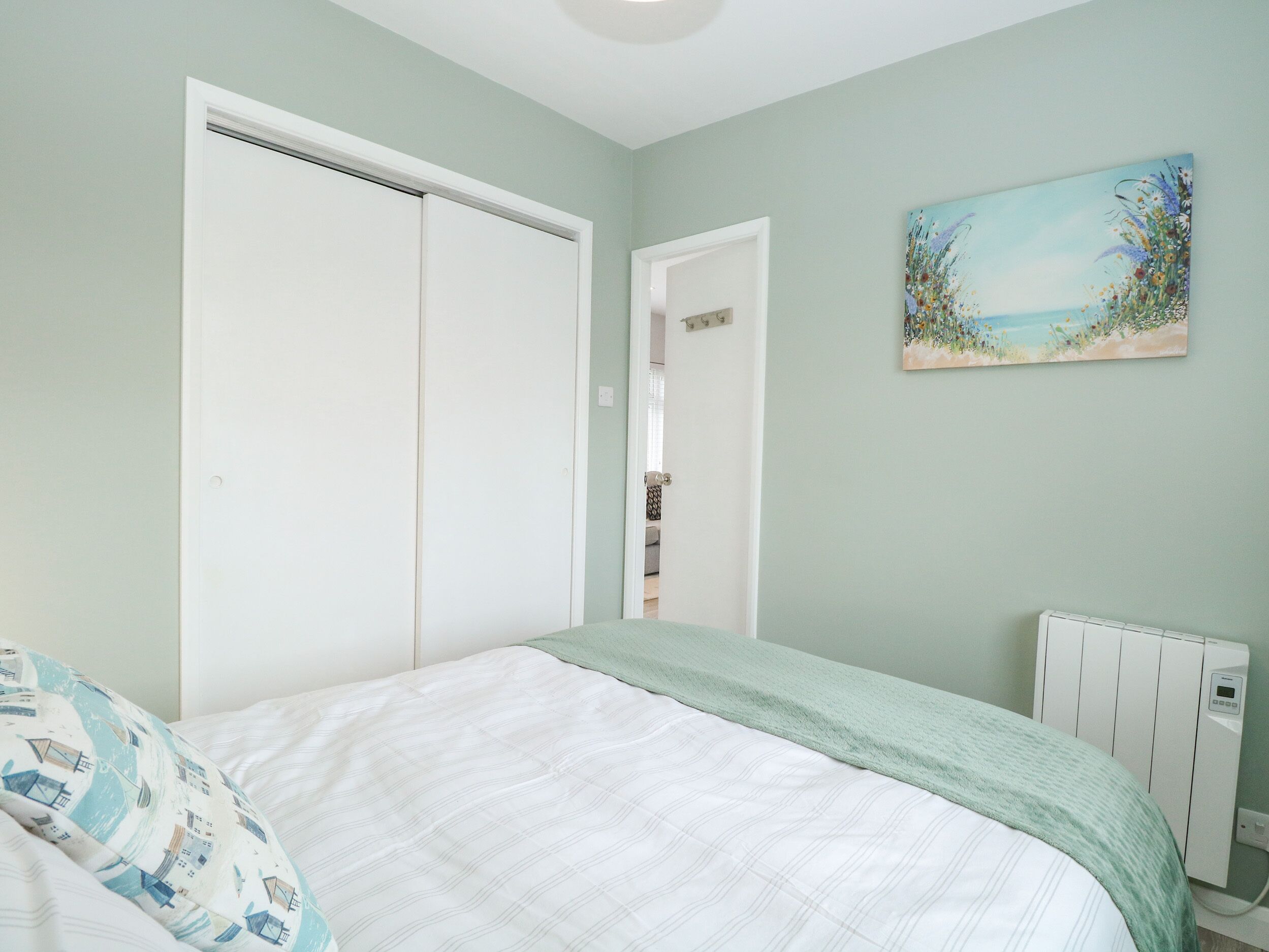 Ein Schlafzimmer mit einem Bett, einem Heizkörper, einer Tür und einem Bild an der Wand.