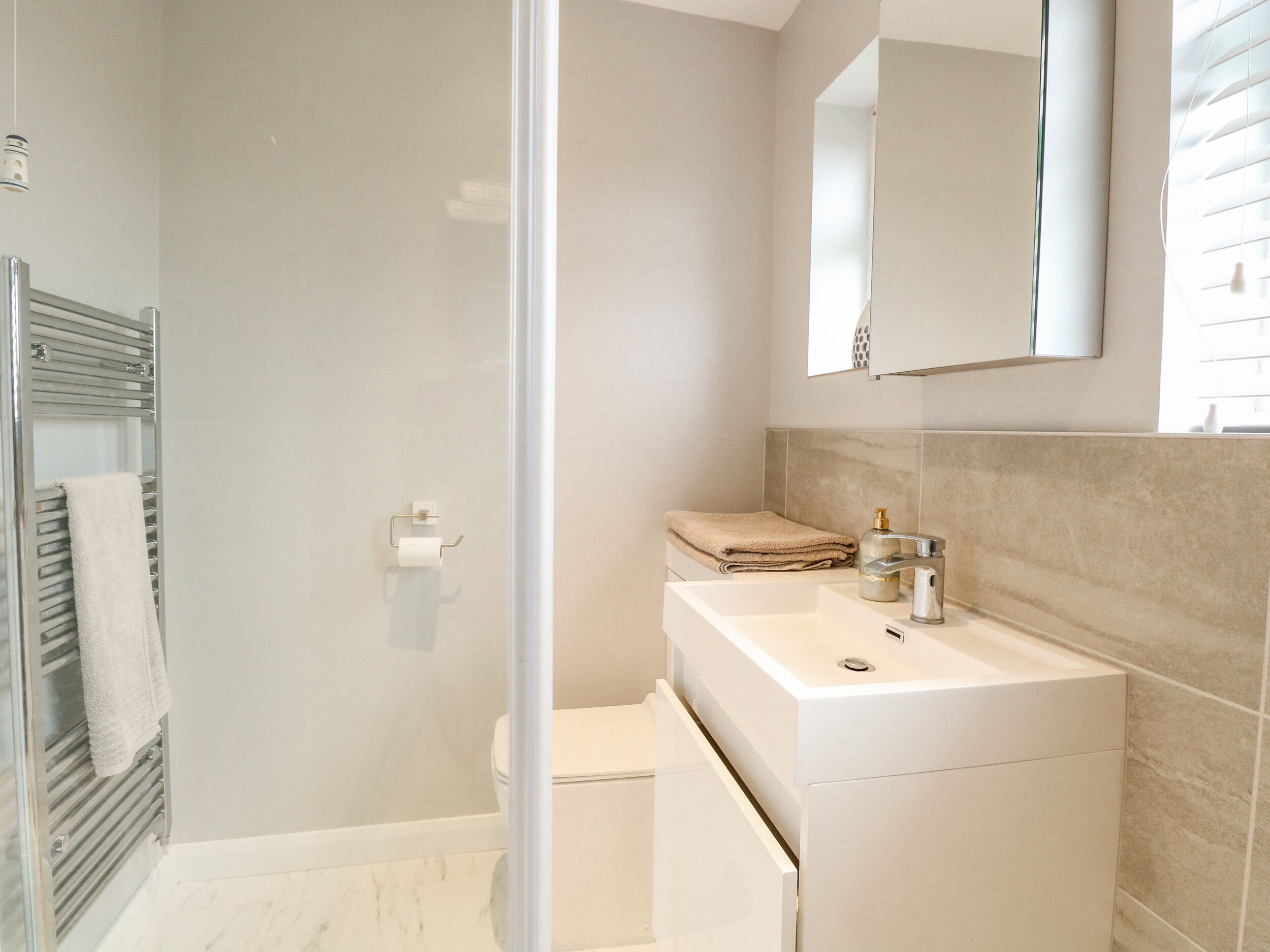 Ein modernes Badezimmer mit Duschkabine aus Glas, einem weißen Waschbecken und einer Toilette.