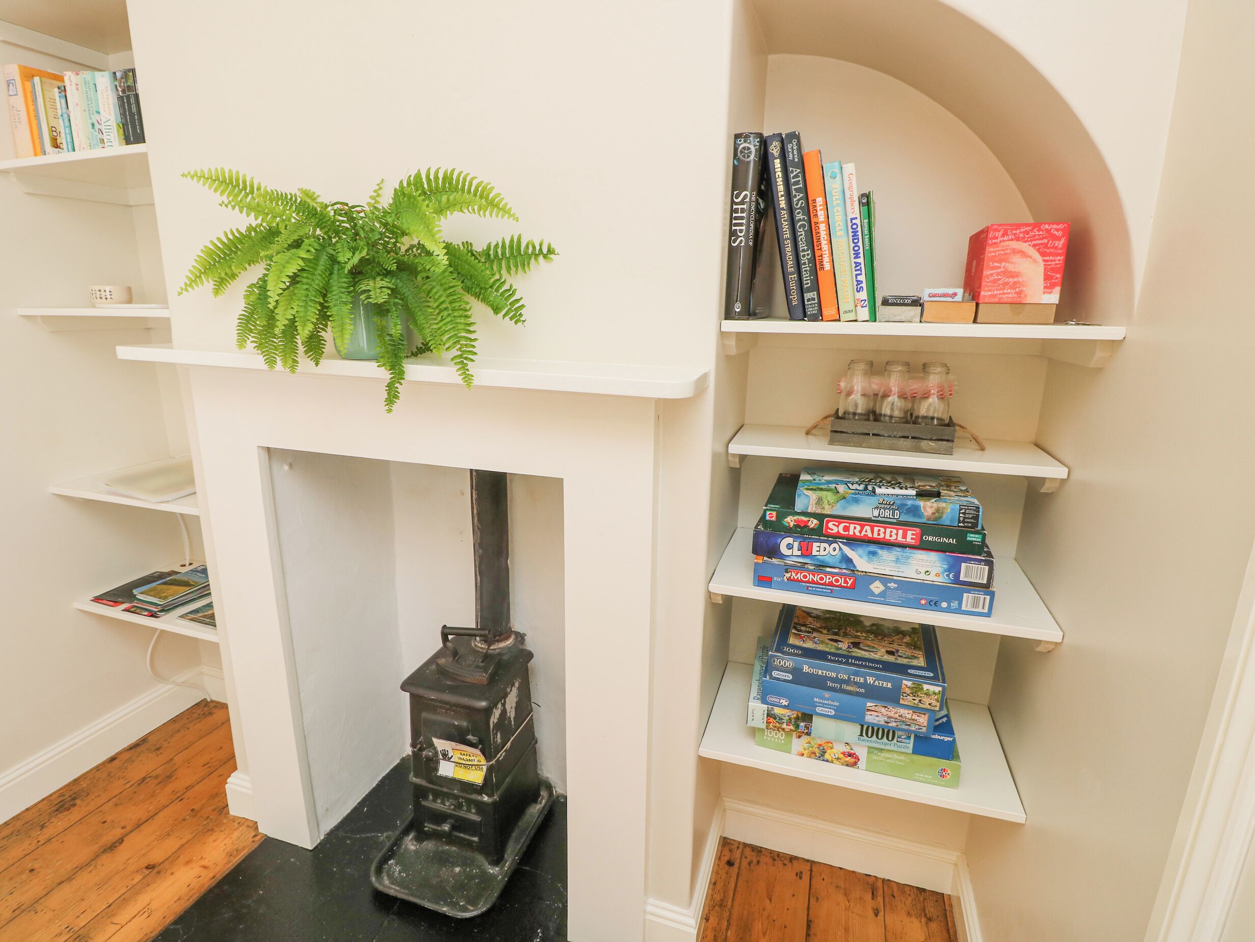 A bookshelf with books, a Scrabble game, and a Monopoly game.