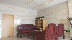Eine moderne Lobby mit einer Holzbank, einem Holzschrank mit Blumentöpfen und einem Empfangstresen.