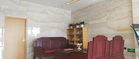 Un vestíbulo moderno con un banco de madera, un mueble de madera con plantas en macetas y un mostrador de recepción.