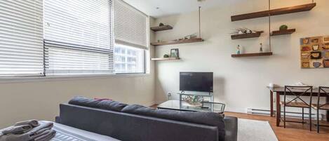 A modern living room with a sofa, TV, and wooden shelves.