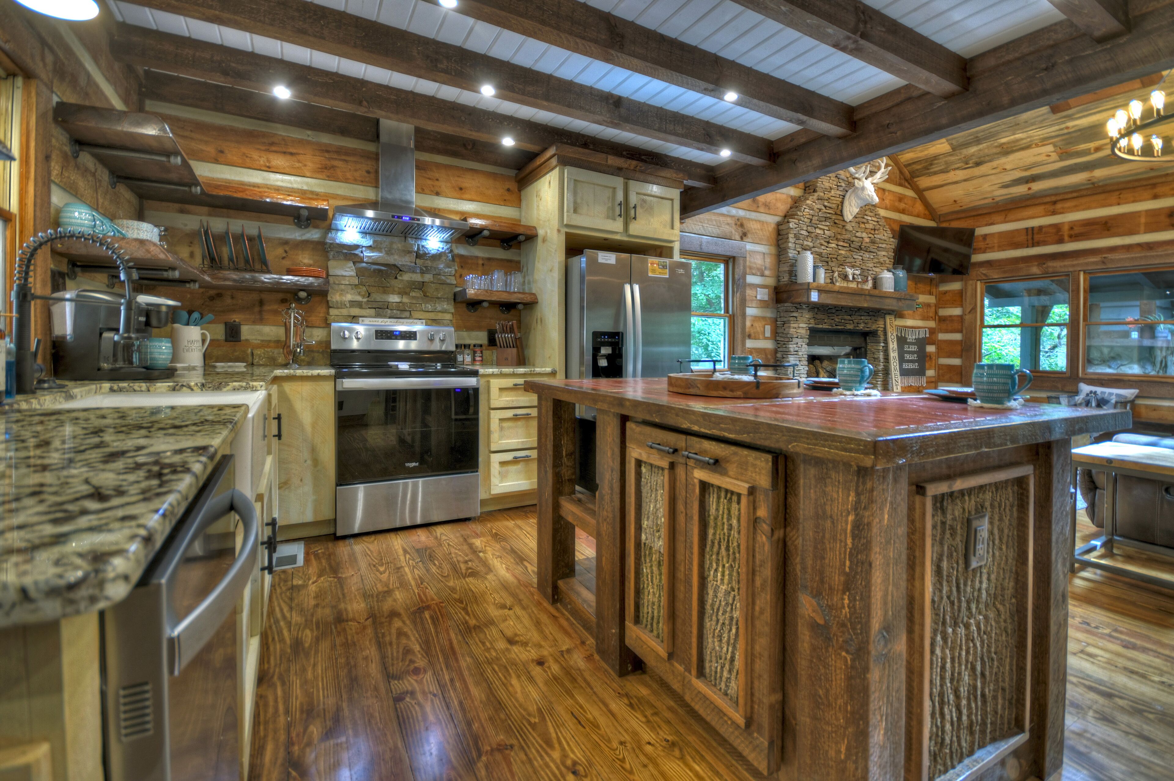 Une cuisine rustique avec des meubles en bois, un grand îlot central, des appareils électroménagers en acier inoxydable et une cheminée en pierre.