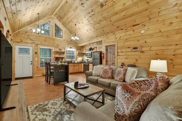 A log cabin interior with a dining area, kitchen, and living room.