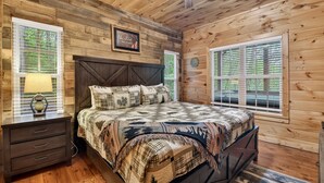 Ein Schlafzimmer einer Holzhütte mit Bett, Nachttisch und Deckenventilator.