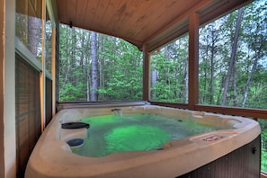 A hot tub with a view of a forest.