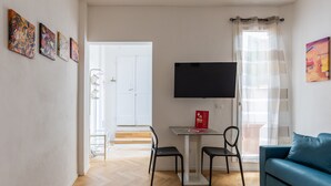 Un salon moderne avec un téléviseur à écran plat, un canapé bleu et une table à manger avec deux chaises.
