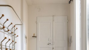 Un couloir avec une porte blanche, un porte-manteau et un plancher en bois.