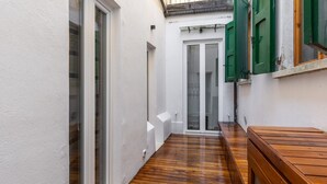 Un couloir étroit doté d’un plancher en bois, de murs blancs et d’une porte coulissante en verre donnant sur une pièce.