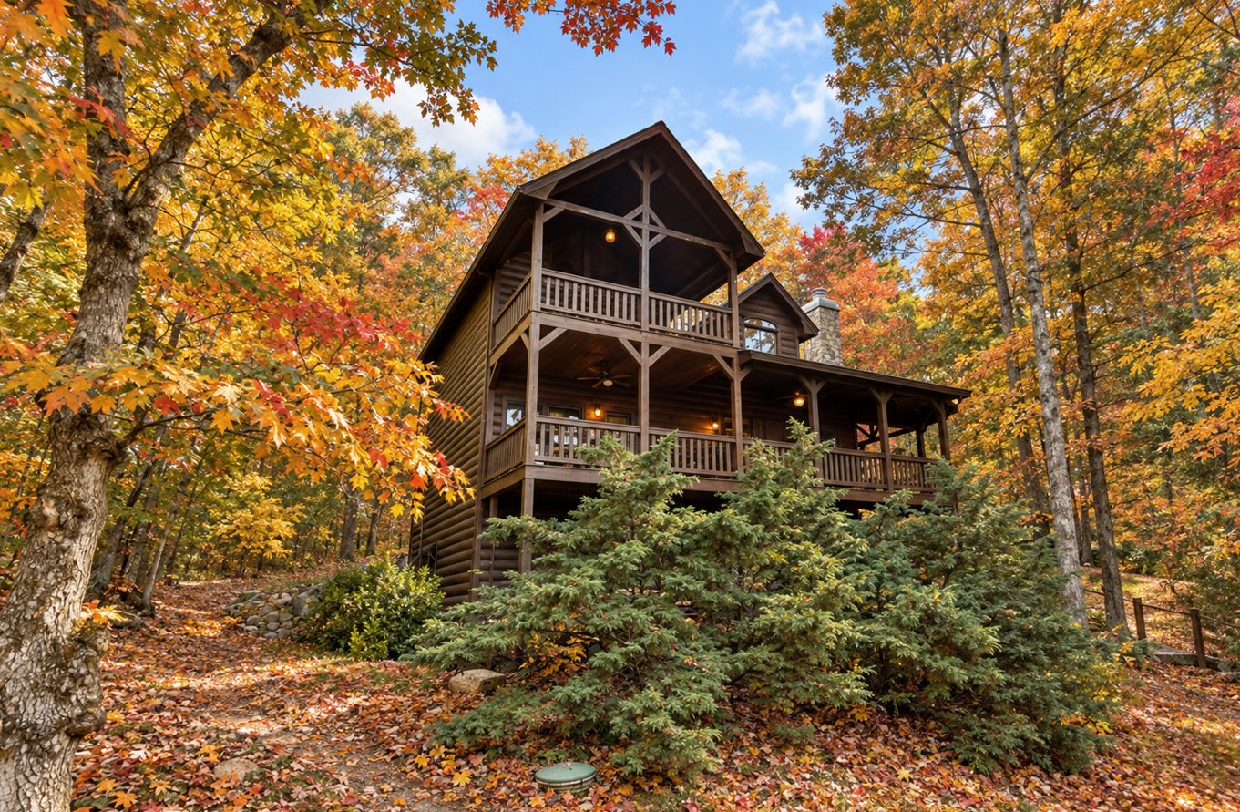 A multi-story log cabin with a balcony, surrounded by autumn foliage.