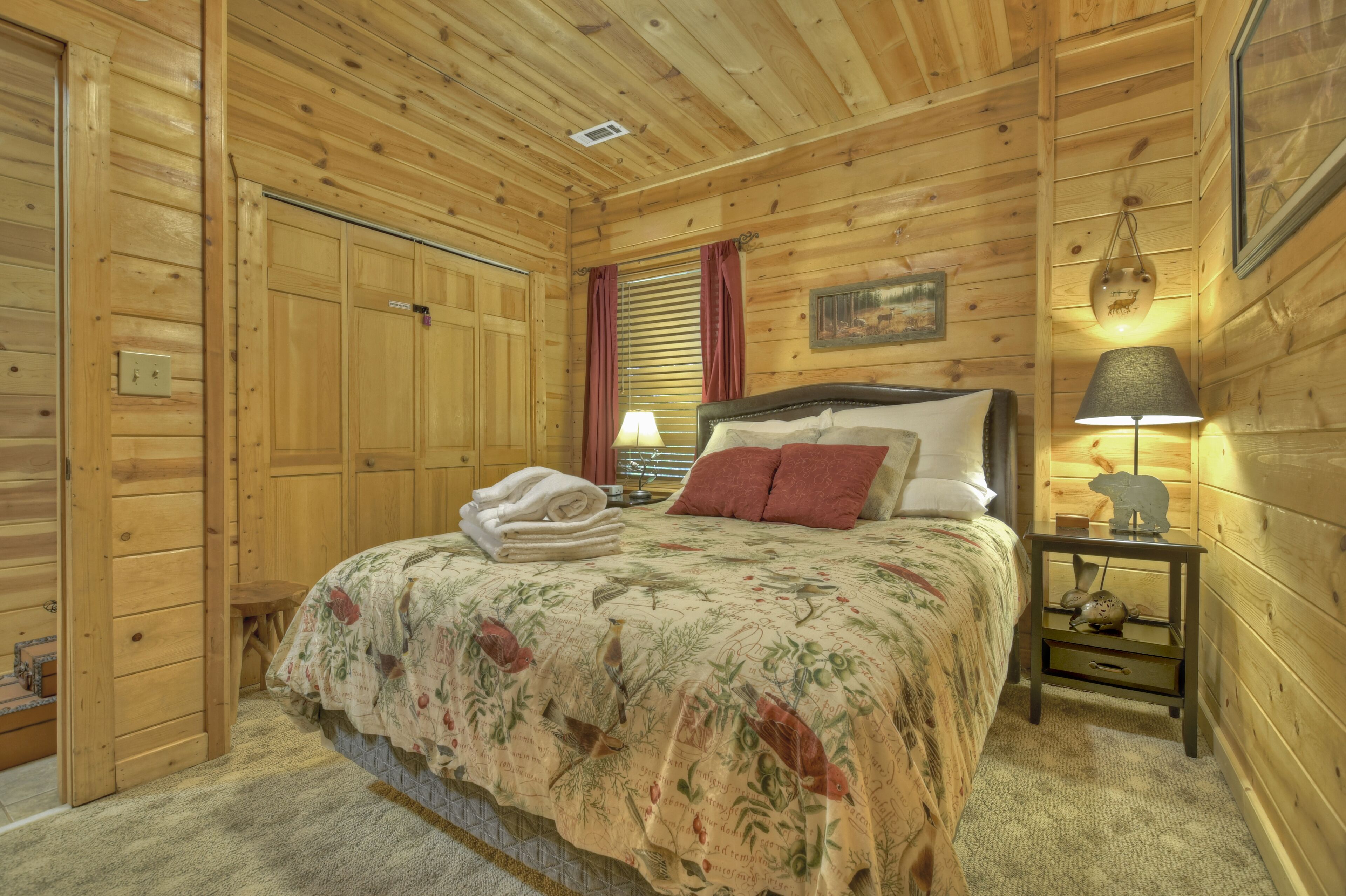Une chambre à coucher dans une cabane en bois, avec un lit, une table de chevet, une lampe et un tableau accroché au mur.