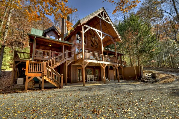 A log cabin with a balcony, a covered porch, and a staircase leading to the upper level.