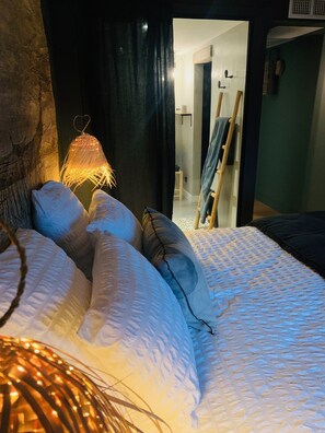 A bedroom with a bed, pillows, a hanging light fixture, and a wooden ladder leaning against the wall. - La Cambrousse (Villers-la-Chèvre)
