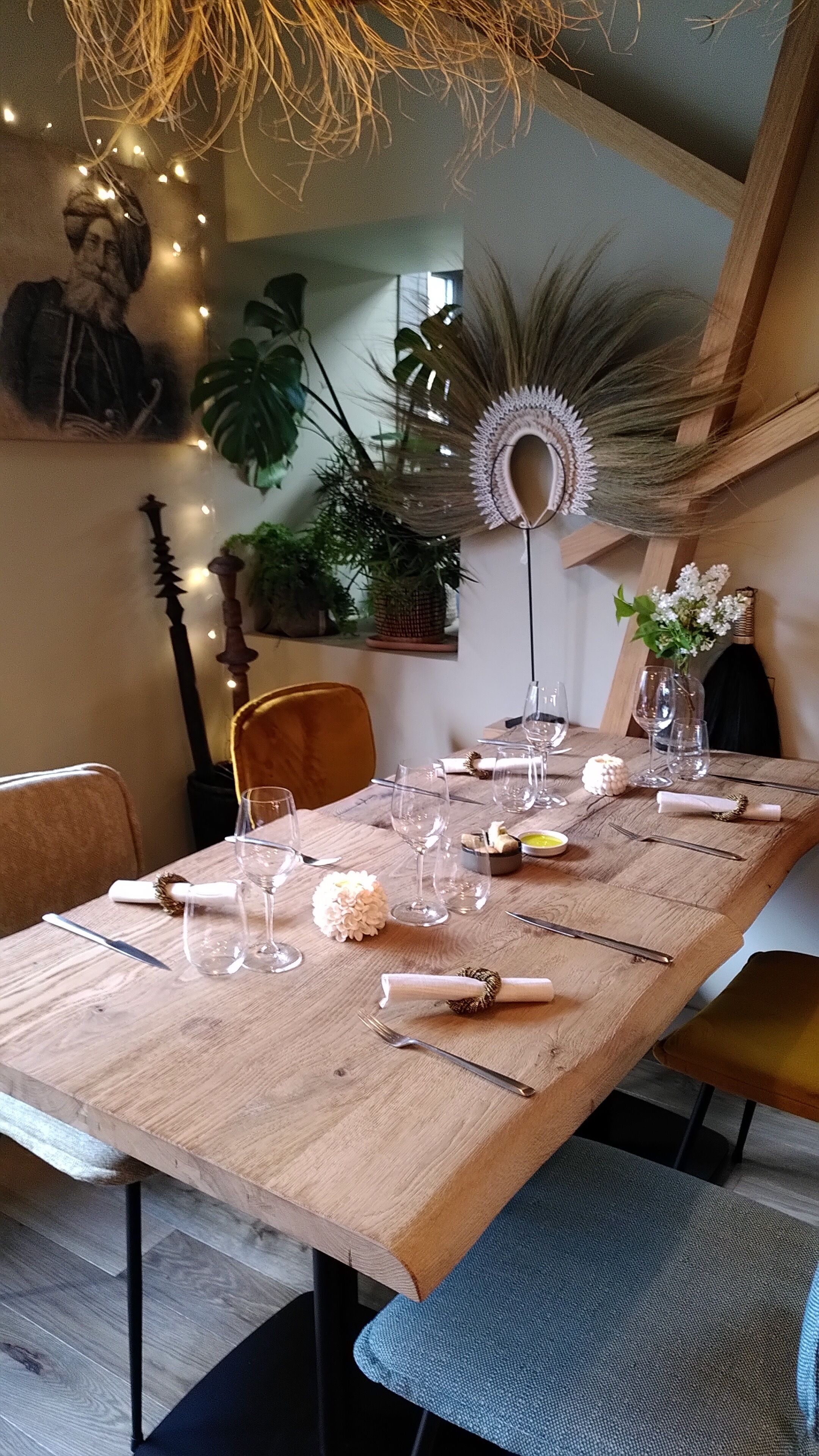 A dining table set with wine glasses, a vase with flowers, and a decorative wall piece.