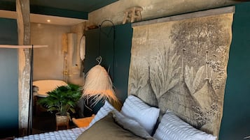 Un dormitorio con una cama grande, una lámpara colgante y una obra de arte en la pared.