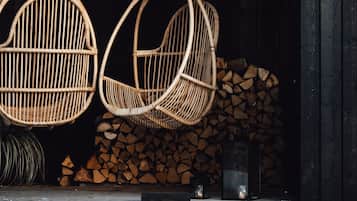 Wicker chairs hanging from a wooden ceiling, a sign reading "HILLTOP HOUSE," and a welcome sign stating "COME ON IN WE ARE OPEN."