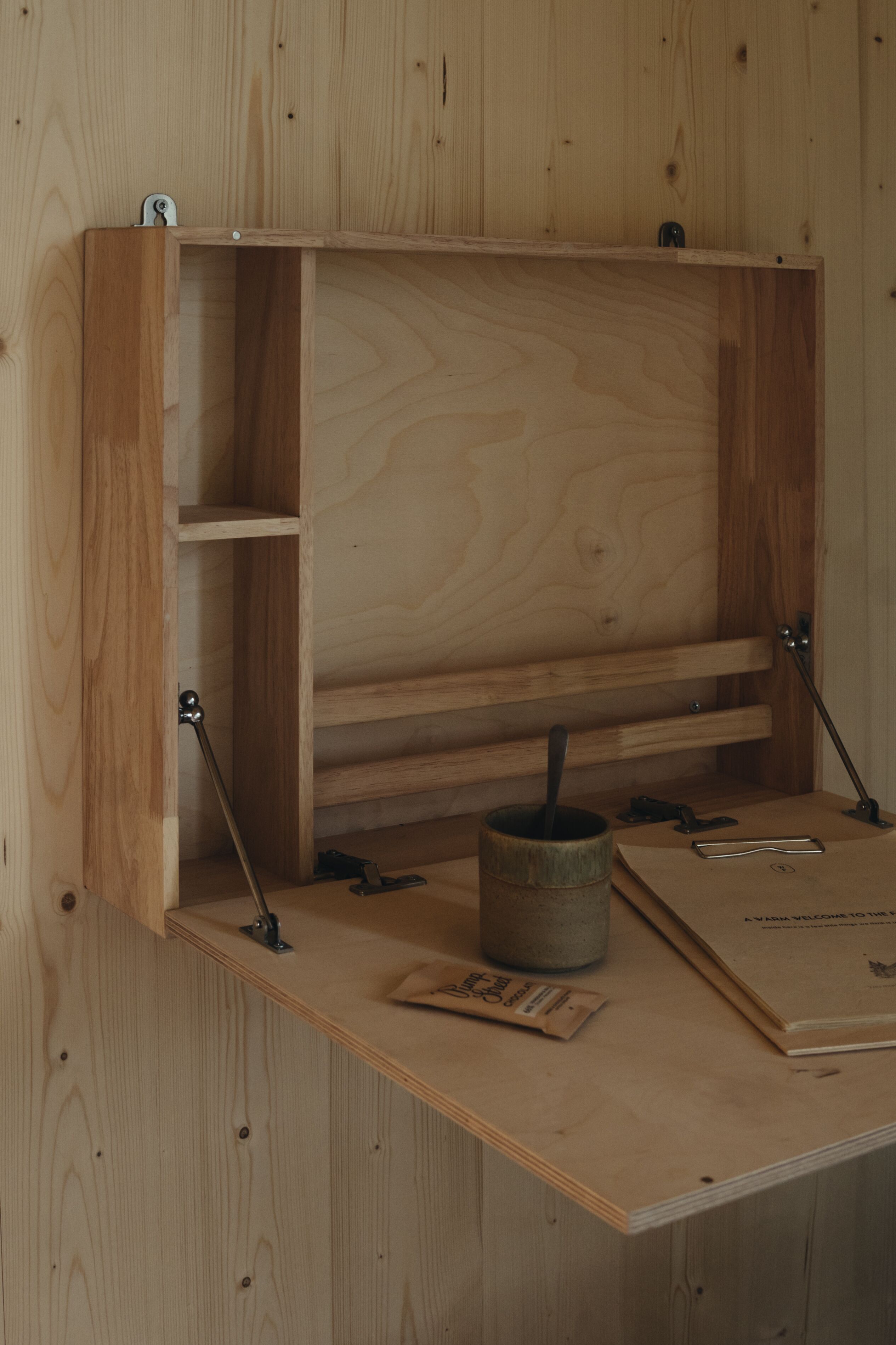 Ein Holztisch mit Regalen, einer Tasse und einem Buch.
