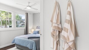 Een slaapkamer met een bed, een raam, een plafondventilator en twee handdoeken aan de muur.