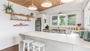 Een moderne keuken met een groot kookeiland, houten planken en hanglampen.
