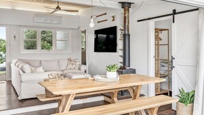 Een moderne woonkamer met een houten eettafel, een bank en een groot raam.