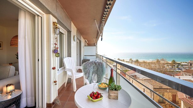 Een balkon met een witte tafel, een fles en een schaal aardbeien.