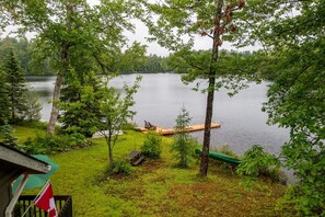 A lakeside property with a dock, a green canoe, and a flag. - Bear Essentials Lakefront Hideaway (Huntsville)