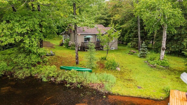 A house surrounded by dense trees and a small stream. - Bear Essentials Lakefront Hideaway (Huntsville)
