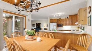 A modern kitchen with wooden cabinets, a central island, and a dining area with a wooden table and chairs. - Bear Essentials Lakefront Hideaway (Huntsville)