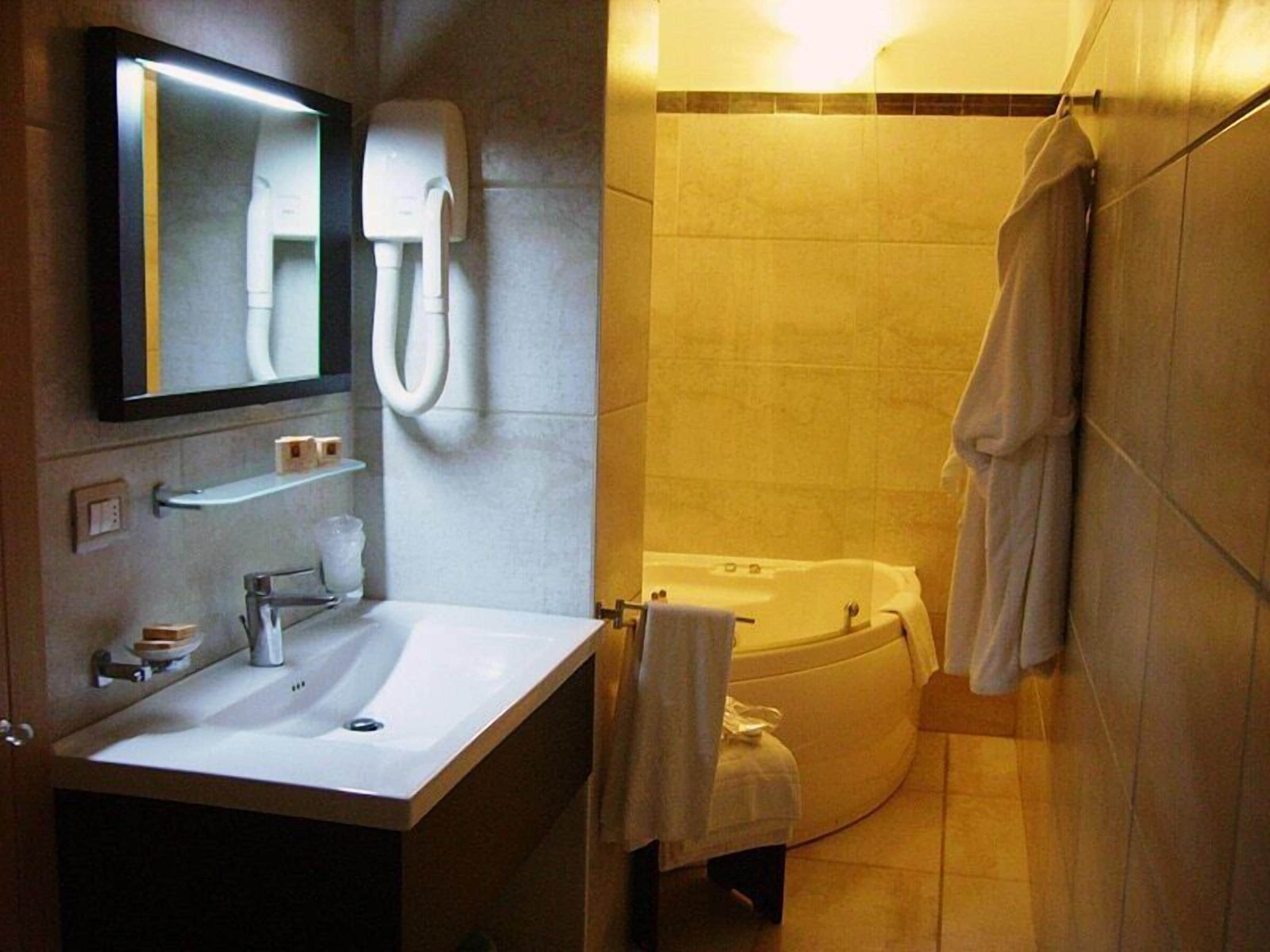 A modern bathroom with a sink, mirror, and bathtub.