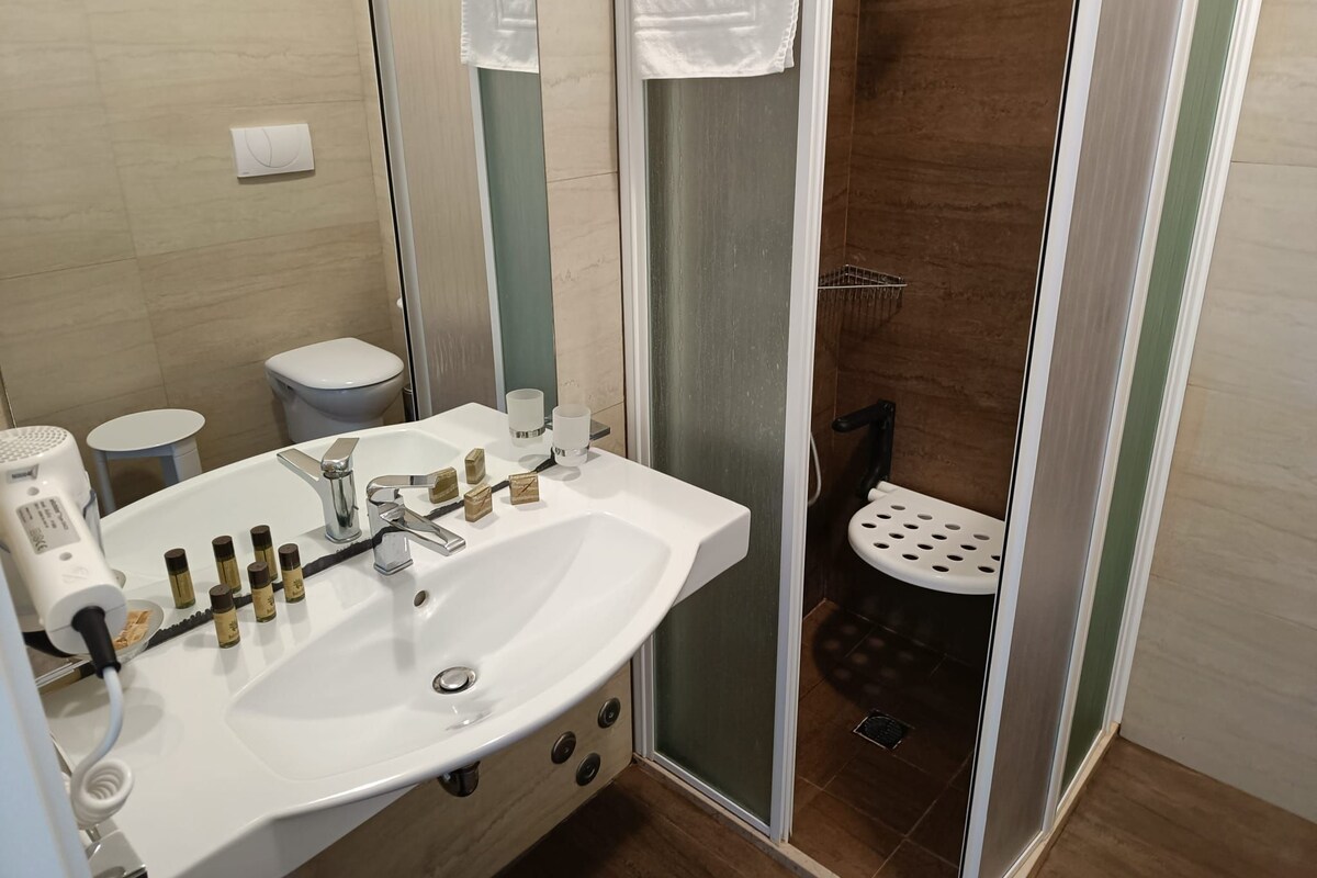 A bathroom with a white sink, a mirror, a toilet, and a shower area.
