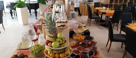 A buffet setup with various fruits, nuts, and beverages.