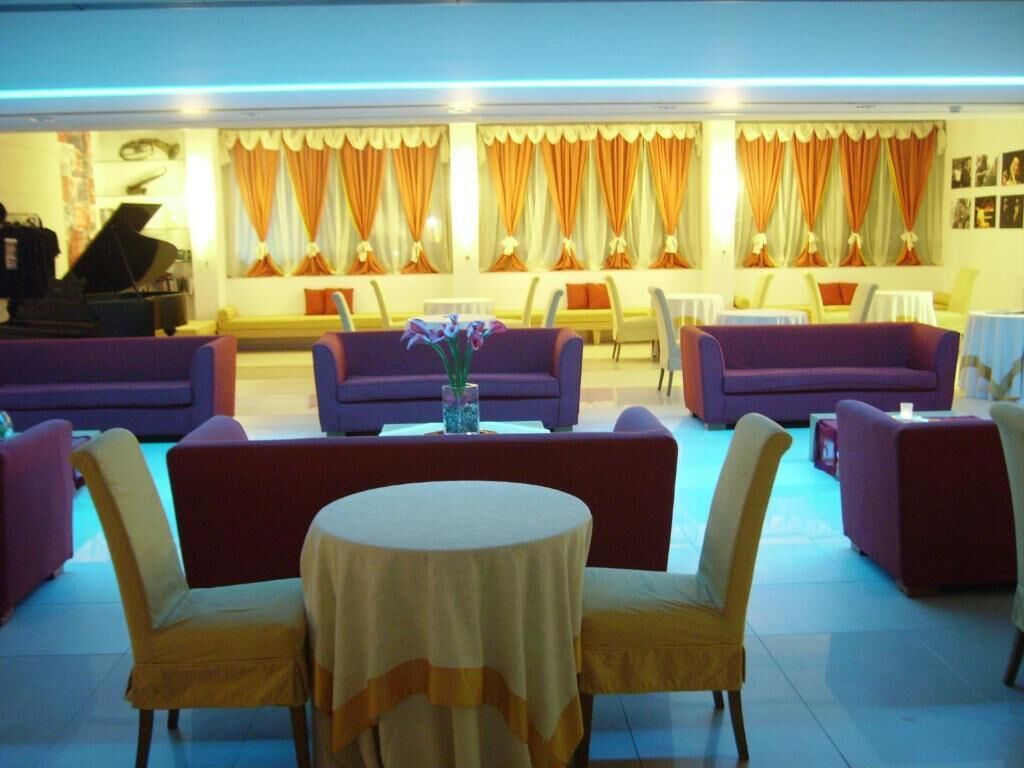 A hotel lobby with purple sofas, a round table, and a piano.