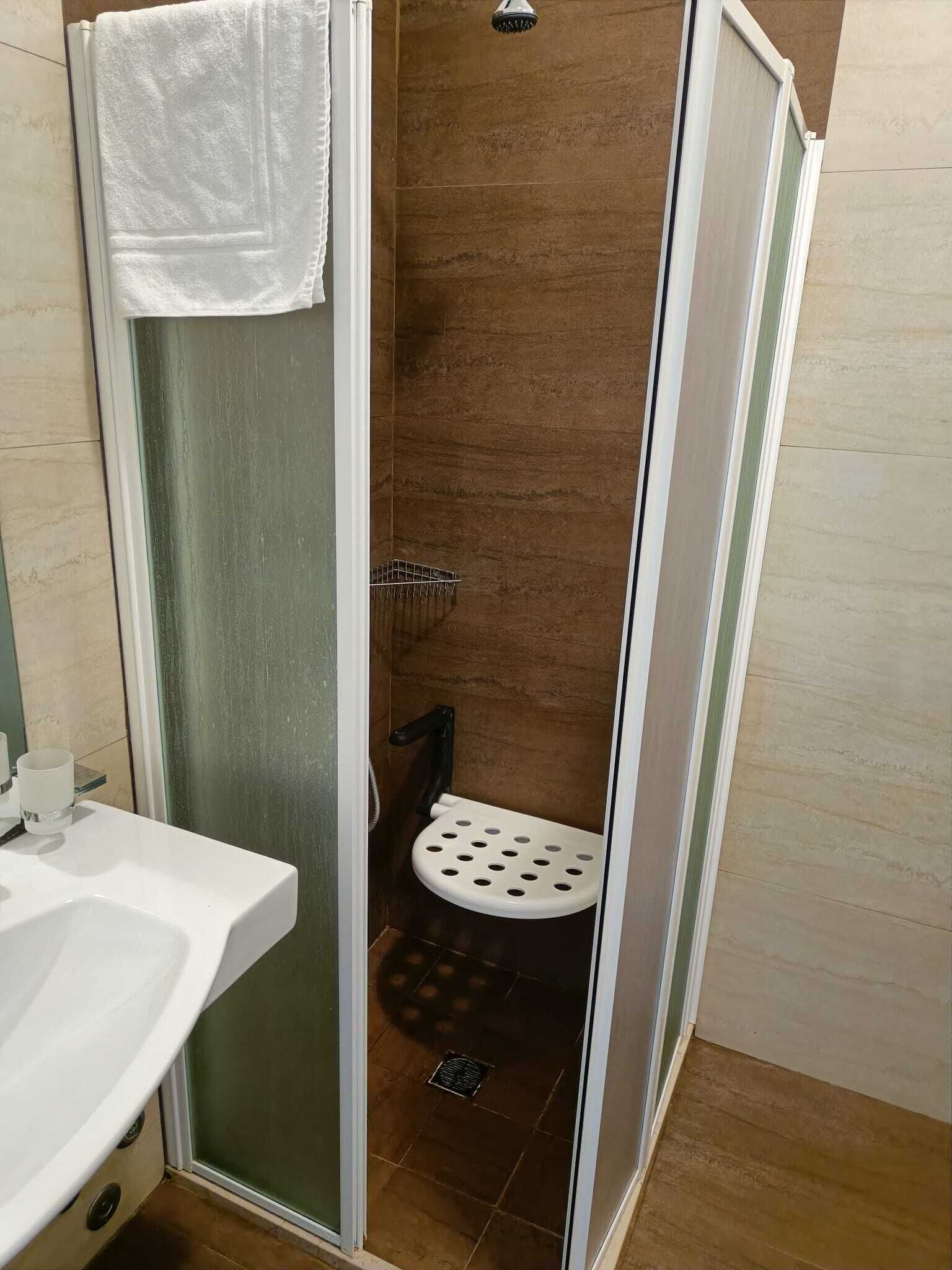 A shower with a glass door, a white toilet, and a sink with a white countertop.